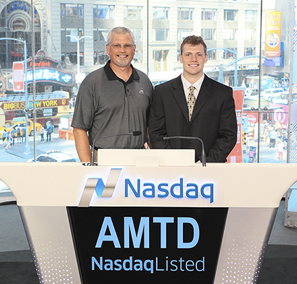 Adam Wilkins with his dad in front of Nasdaq podium, Times Square can be seen thru the window in background