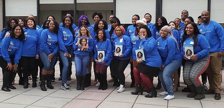 group photo, several students wearing blue EOP t-shirts and holding books in their hand
