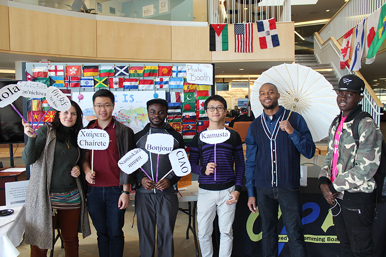 students and staff holding signs that say hello in different languages, many different flags