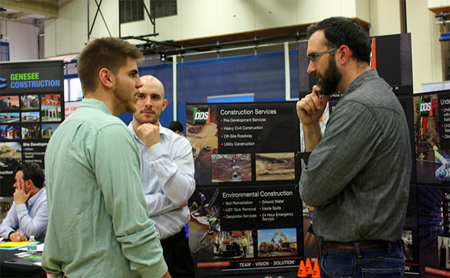 student speaking with two men at career fair