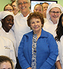 Evelyn Turner surrounded by students wearing their white culinary uniforms and hats