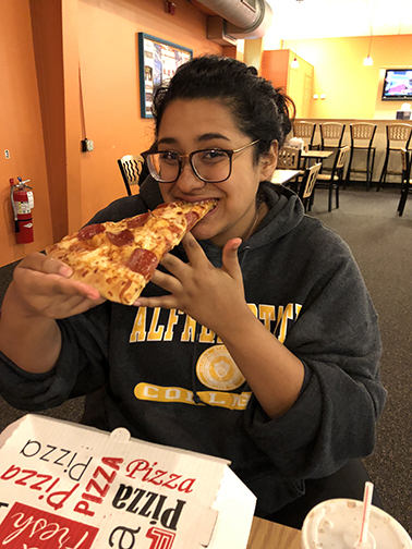 female student eating a slice of pizza