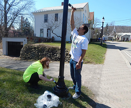 Juliana Krajewski and Abraham Kalamadeen paint a Victorian street light pole on Main Street 