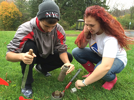 Two students take a sample of soil to analyze