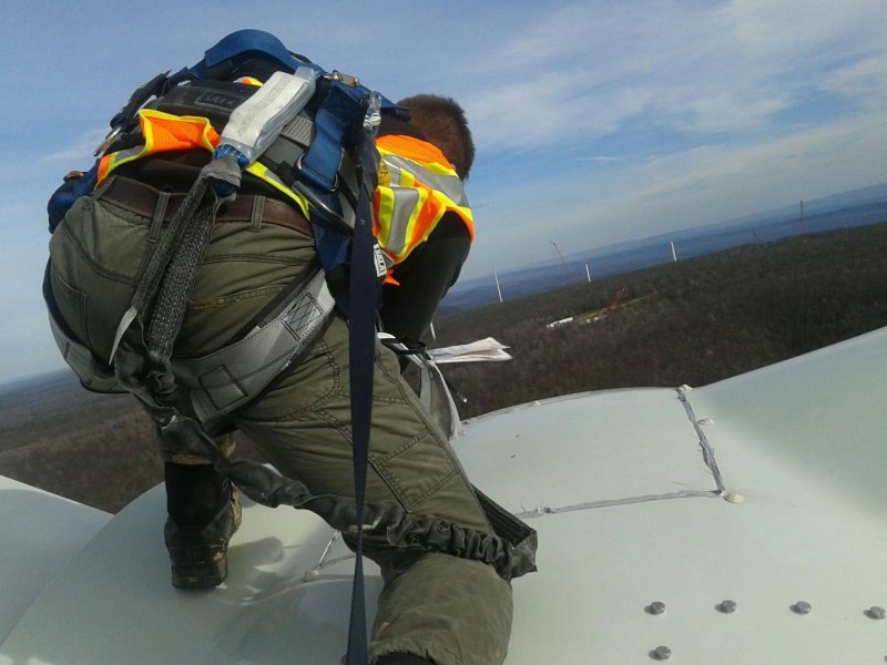 Alfred State grad - top of the hub -windmill, back view of grad wearing safety harness